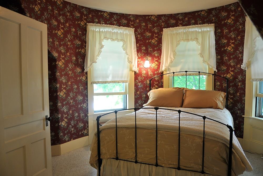 Tower Room with queen-size rail bed and floral wallpaper